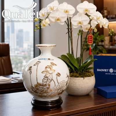 Bình hút tài lộc dặt trang trọng trên bàn làm việc gỗ bên cạnh chậu lan hồ diệp và hộp quà thương hiệu