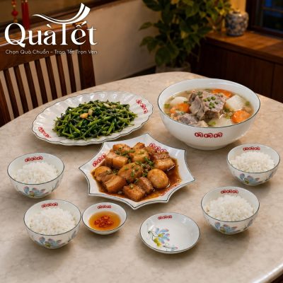 Mâm cơm gia đình ngày Tết ấm cúng được bày biện tinh tươm trên bộ bát đĩa vẽ sen