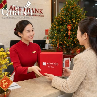 Giao dịch viên ngân hàng trao gửi hộp quà Tết đỏ may mắn cho khách hàng tại quầy