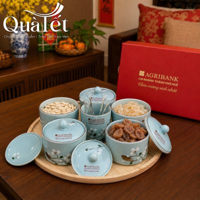 Hũ sứ men xanh pastel bóng mịn đựng đầy hạt hướng dương và mứt gừng dẻo thơm ngon.