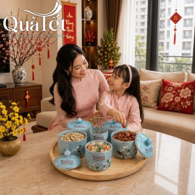 Hai mẹ con mặc áo dài hồng đồng điệu cùng nhau thưởng thức mứt Tết bày trên khay sứ men xanh
