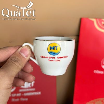 Cận cảnh chiếc chén trà sứ trắng nhỏ xinh viền chỉ vàng kim in logo MT sắc nét trên thân chén