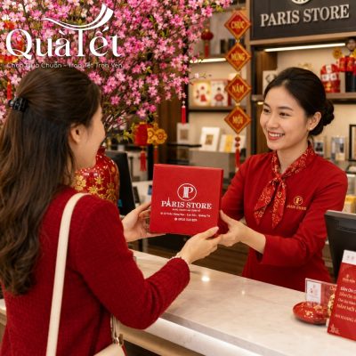 Nữ nhân viên Paris Store mặc áo dài đỏ trao tận tay hộp quà Tết cho khách hàng tại quầy