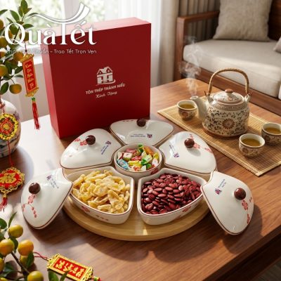 Khay mứt dáng hoa vẽ đào đỏ đặt trang trọng trên bàn gỗ cùng các loại mứt tết truyền thống