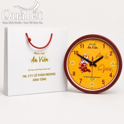 Trọn bộ sản phẩm đồng hồ QT-DH04 đặt cạnh túi giấy quai xách màu đỏ đồng bộ in thương hiệu An Viên.