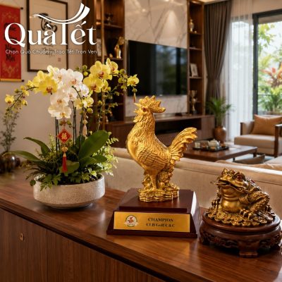 Tượng gà vinh danh mạ vàng QT-TG01 được trưng bày trên kệ gỗ phòng khách cạnh chậu lan hồ điệp vàng