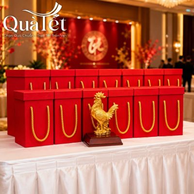 Dàn hộp quà tặng màu đỏ xếp ngay ngắn tại khu vực sảnh sự kiện với tượng gà mạ vàng QT-TG01 đặt ở vị trí trung tâm